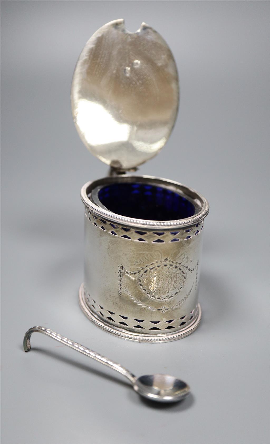 A George III pierced silver oval mustard pot, maker, W?, London, 1785, with blue glass liner and associated plated spoon.